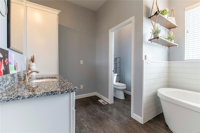 bathroom featuring a tub, hardwood / wood-style flooring, vanity, and toilet