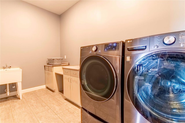 laundry area with washing machine and clothes dryer, cabinets, and light tile patterned flooring