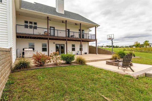 back of house featuring a balcony, a patio, a yard, and a fire pit