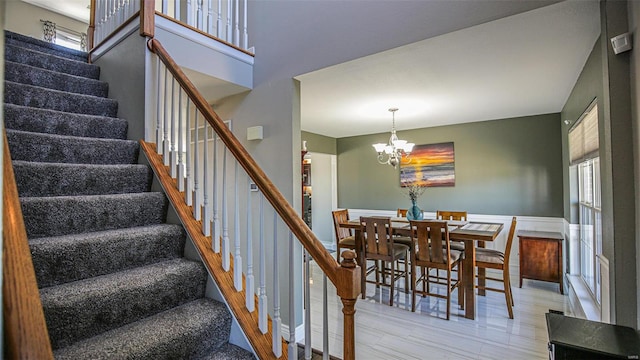 stairway with a notable chandelier, hardwood / wood-style flooring, and a wealth of natural light