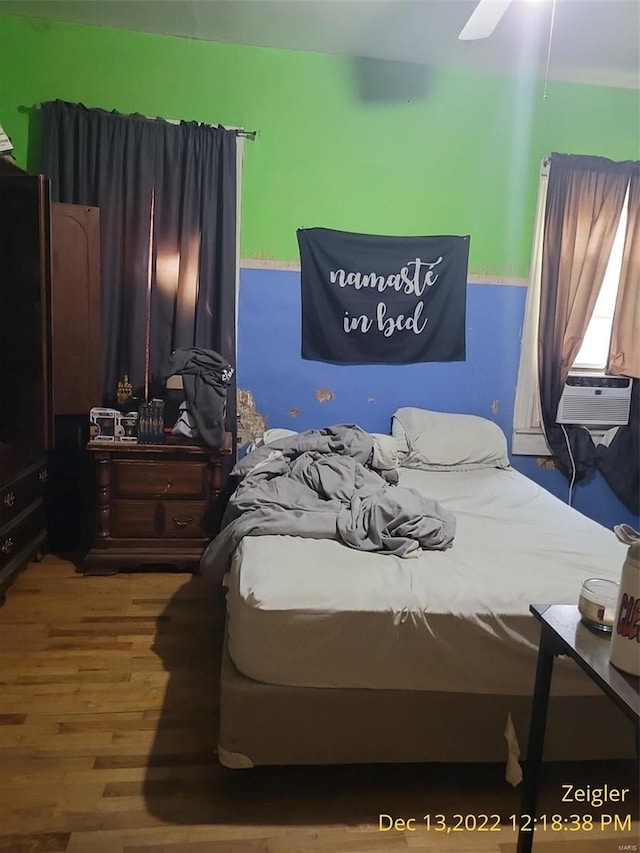 bedroom with wood-type flooring, ceiling fan, and cooling unit