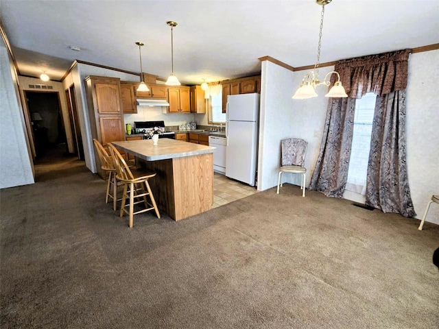 kitchen with pendant lighting, ornamental molding, white appliances, and a kitchen island