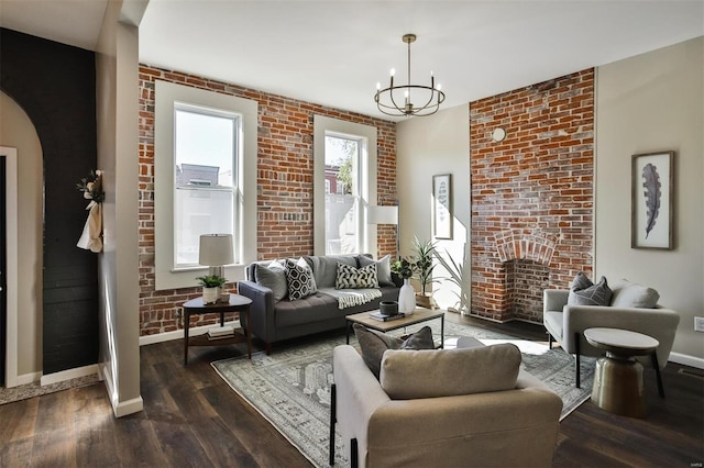 living room featuring a notable chandelier, brick wall, and dark hardwood / wood-style flooring