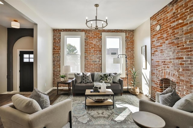 living room with brick wall, hardwood / wood-style flooring, and a chandelier