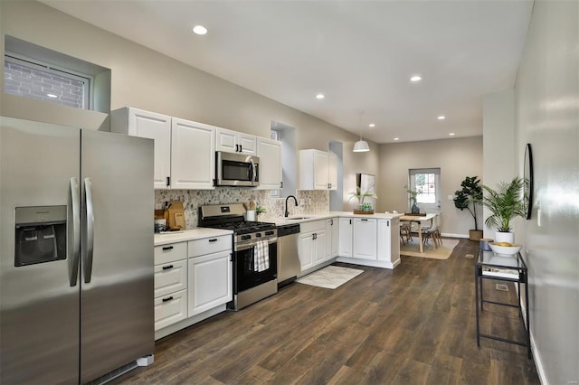 kitchen with dark hardwood / wood-style floors, sink, white cabinetry, kitchen peninsula, and appliances with stainless steel finishes