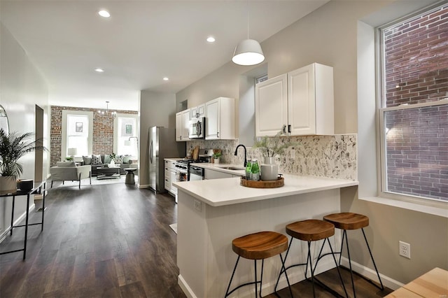 kitchen with dark hardwood / wood-style floors, white cabinetry, a kitchen breakfast bar, appliances with stainless steel finishes, and decorative light fixtures