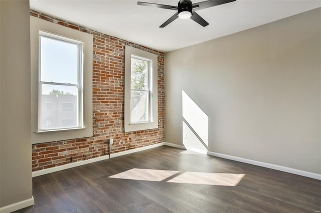 spare room with dark hardwood / wood-style floors, ceiling fan, and brick wall