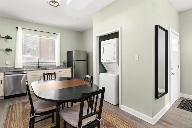 dining space featuring stacked washer and dryer, sink, and light hardwood / wood-style flooring