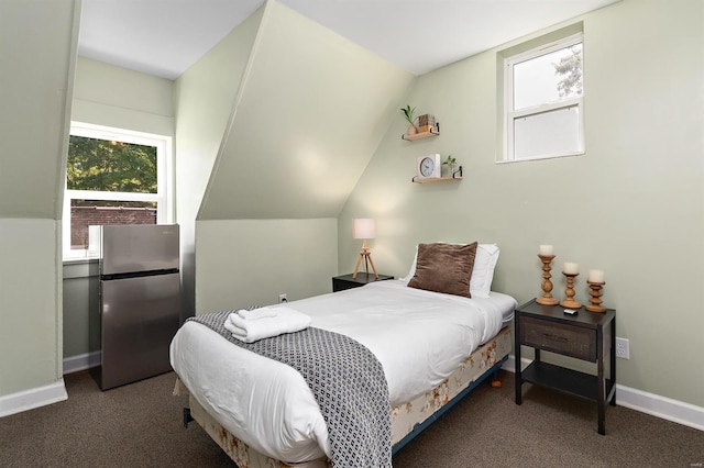 carpeted bedroom with stainless steel refrigerator and lofted ceiling