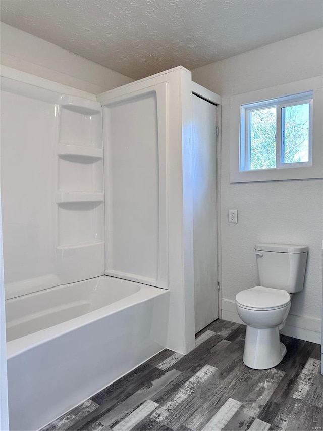 bathroom with hardwood / wood-style floors, a textured ceiling, toilet, and shower / bathtub combination