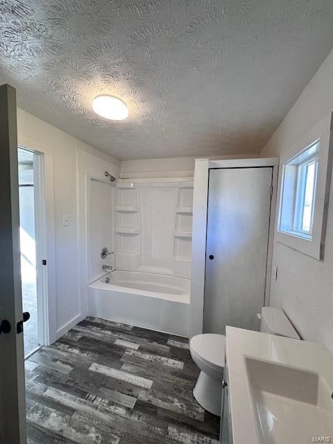 full bathroom featuring hardwood / wood-style flooring, toilet, shower / bathing tub combination, vanity, and a textured ceiling