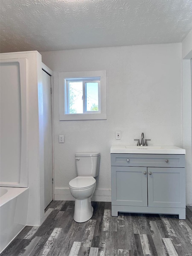 full bathroom featuring vanity, hardwood / wood-style floors, a textured ceiling, and toilet