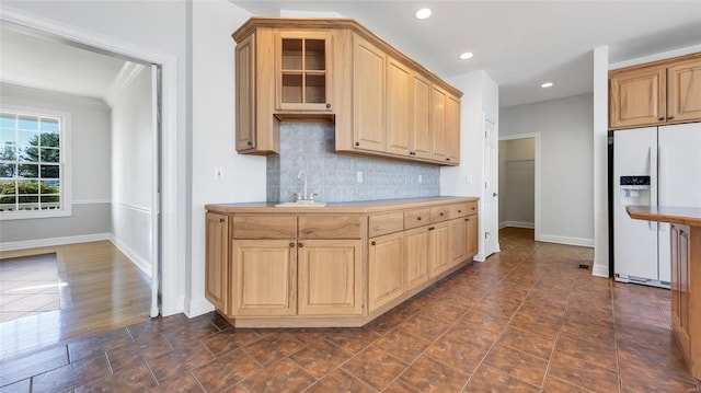 kitchen featuring decorative backsplash, sink, ornamental molding, light brown cabinetry, and white fridge with ice dispenser