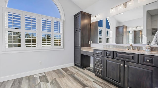 bathroom featuring hardwood / wood-style floors, vanity, and lofted ceiling