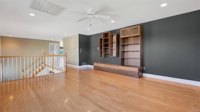 unfurnished living room featuring light wood-type flooring, ceiling fan, and built in shelves