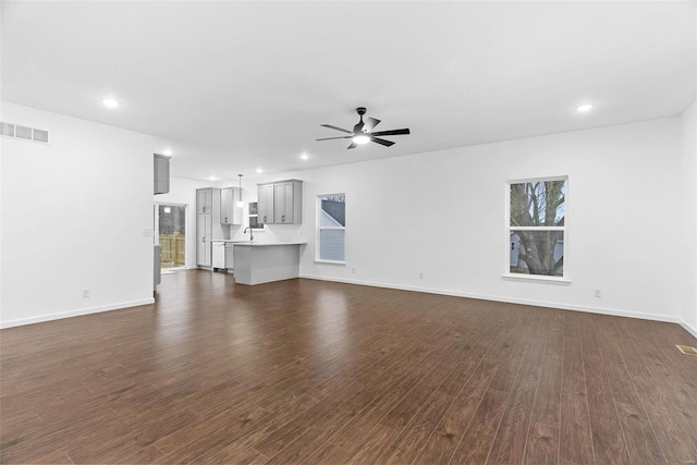 unfurnished living room with dark wood-type flooring, ceiling fan, and sink