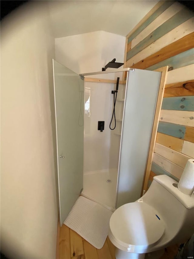 bathroom with hardwood / wood-style flooring, a shower, and toilet