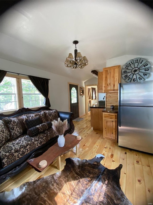 living room featuring vaulted ceiling, light hardwood / wood-style flooring, and a chandelier