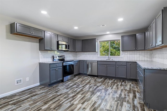 kitchen featuring gray cabinets, stainless steel appliances, dark wood-type flooring, and sink