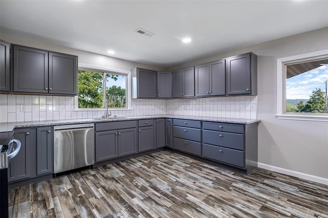 kitchen featuring gray cabinetry, appliances with stainless steel finishes, a wealth of natural light, and dark hardwood / wood-style floors