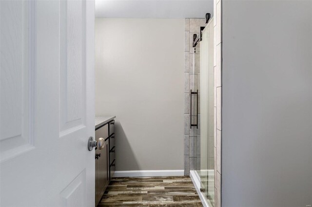 bathroom featuring vanity, wood-type flooring, and a shower with door