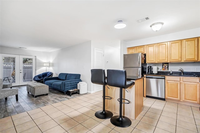 kitchen with a kitchen island, sink, a breakfast bar area, appliances with stainless steel finishes, and light tile patterned floors