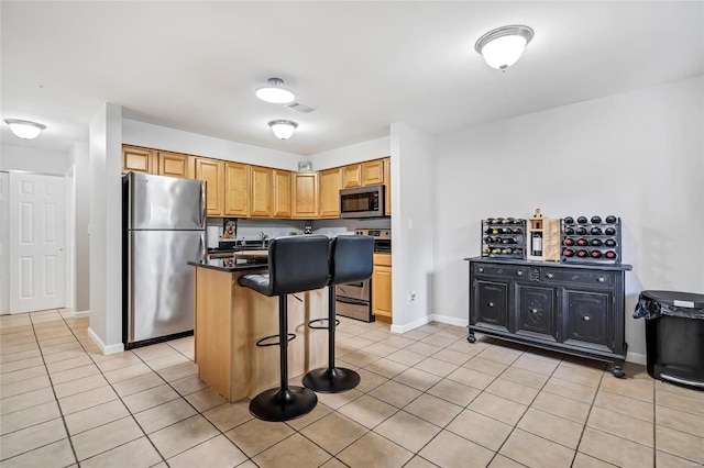 kitchen with a kitchen island, a breakfast bar, sink, appliances with stainless steel finishes, and light tile patterned floors