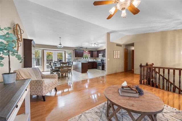 living room with light hardwood / wood-style floors, vaulted ceiling, and ceiling fan