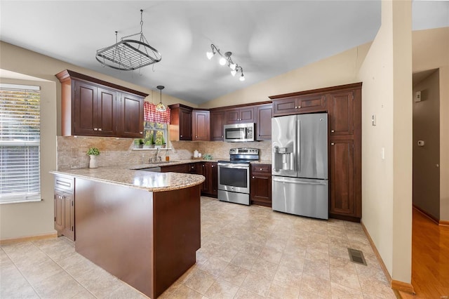 kitchen featuring lofted ceiling, stainless steel appliances, hanging light fixtures, and a wealth of natural light