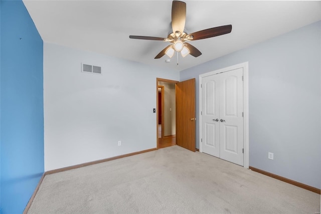 unfurnished bedroom with light colored carpet, a closet, and ceiling fan