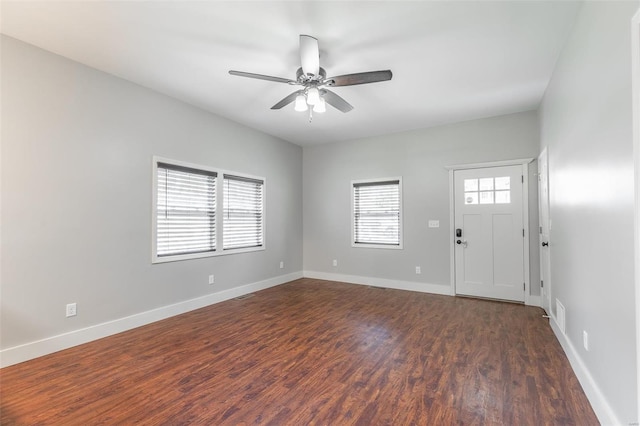 interior space with baseboards, a ceiling fan, and dark wood-style floors