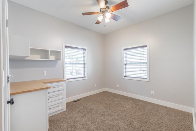 unfurnished office featuring baseboards, ceiling fan, carpet flooring, and visible vents