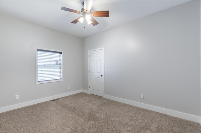 spare room with light colored carpet, ceiling fan, visible vents, and baseboards
