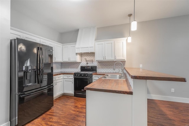 kitchen with decorative backsplash, a peninsula, butcher block counters, a sink, and black appliances