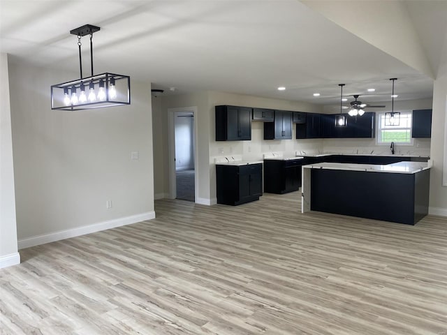 kitchen featuring a kitchen island, pendant lighting, light wood-type flooring, ceiling fan, and sink