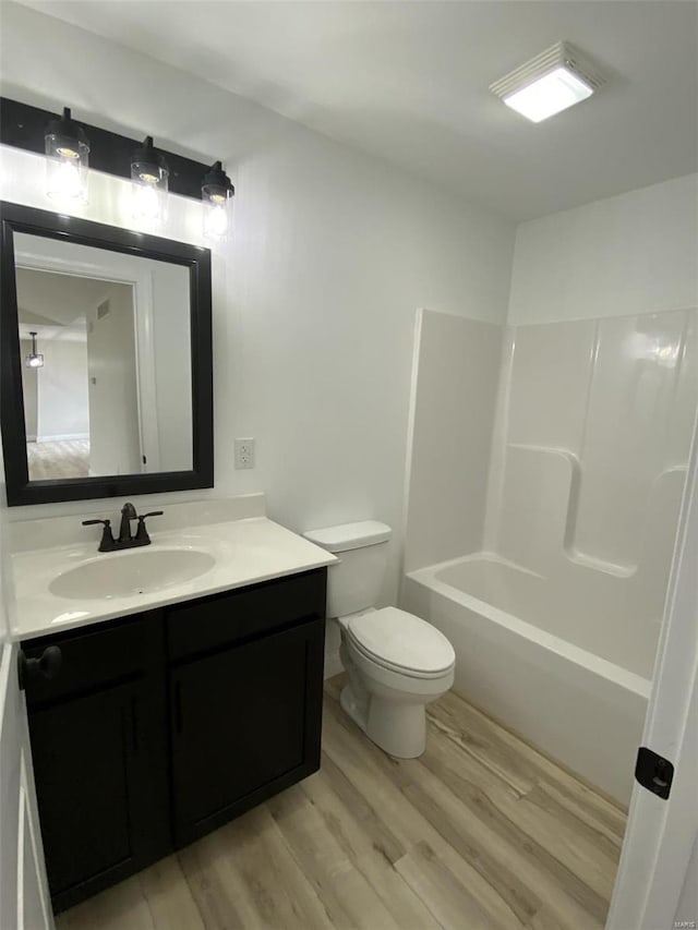 full bathroom with shower / bathing tub combination, hardwood / wood-style flooring, vanity, and toilet