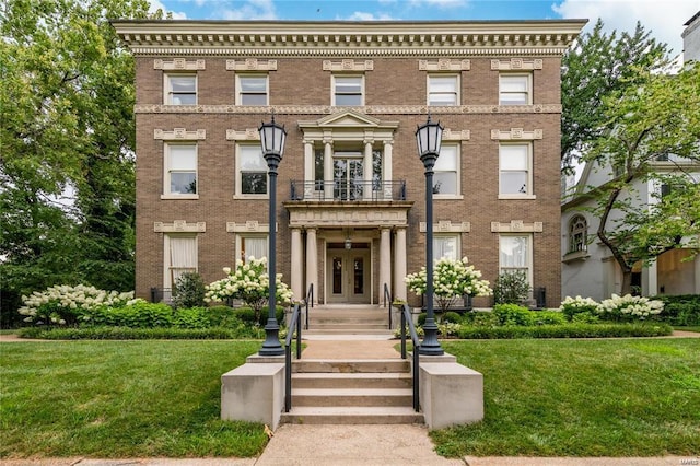 view of front of property with a balcony, a front yard, and french doors