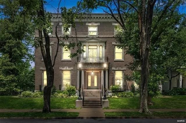 italianate-style house with a balcony and a front lawn