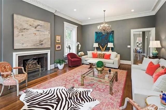 living room with ornamental molding, a chandelier, a high end fireplace, and hardwood / wood-style flooring