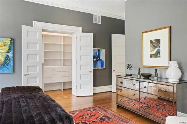 bedroom featuring wood-type flooring, a closet, and ornamental molding