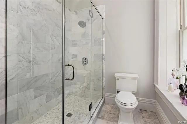 bathroom with a shower with shower door and toilet