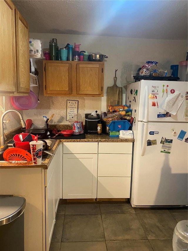 kitchen with dark tile patterned flooring, white refrigerator, and sink