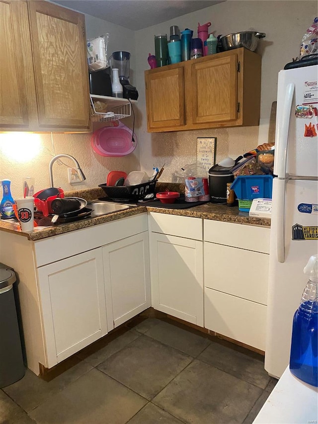 kitchen featuring sink, white fridge, and dark tile patterned floors