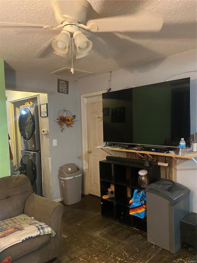 living room with ceiling fan, a textured ceiling, and stacked washer / dryer