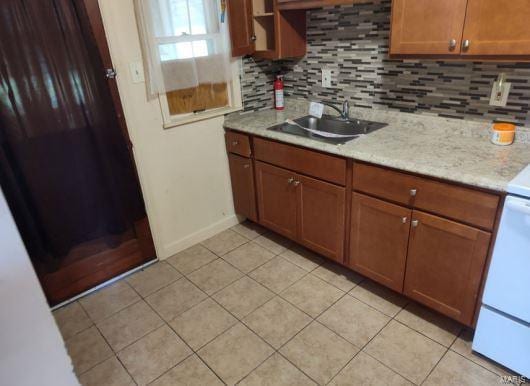 kitchen with light stone countertops, backsplash, and sink