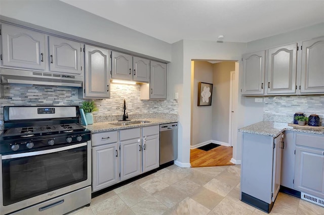 kitchen with sink, extractor fan, gray cabinets, stainless steel appliances, and decorative backsplash