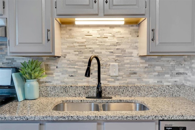 kitchen featuring light stone counters, sink, tasteful backsplash, and white cabinetry