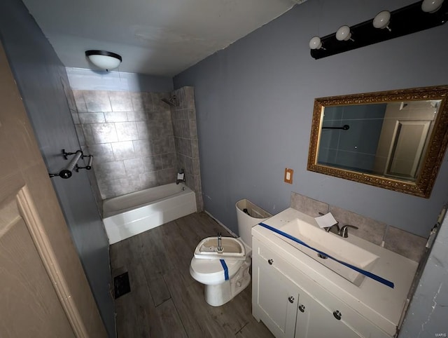 bathroom featuring tiled shower, vanity, toilet, and hardwood / wood-style flooring