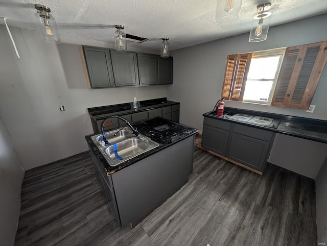 kitchen with sink, a textured ceiling, decorative light fixtures, gray cabinets, and dark hardwood / wood-style flooring