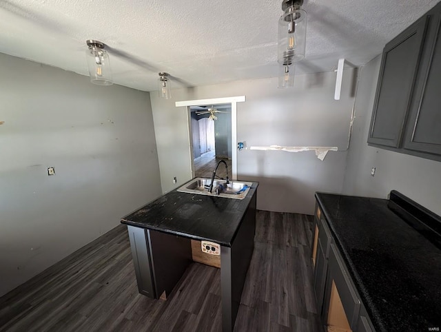 kitchen featuring ceiling fan, sink, a kitchen island, a textured ceiling, and dark wood-type flooring